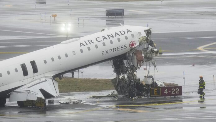 A firefighter walks the site, Monday, March 23, 2026, where an Air Canada jet came to rest after colliding with a Port Authority fire truck at LaGuardia Airport, after landing Sunday night in New York. (AP Photo/Seth Wenig)
